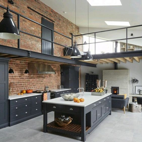 Cocina en espacio diáfano con doble altura estilo industrial.