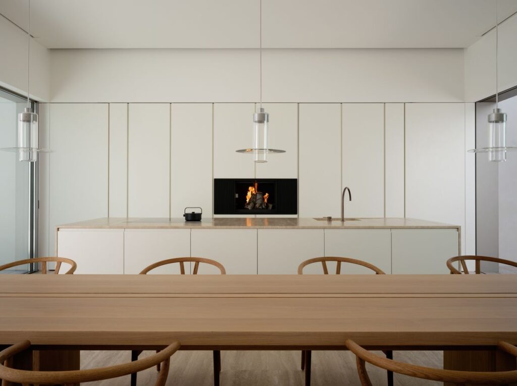 Cocina blanca con mesa y sillas de antecomedor de madera clara estilo minimalista